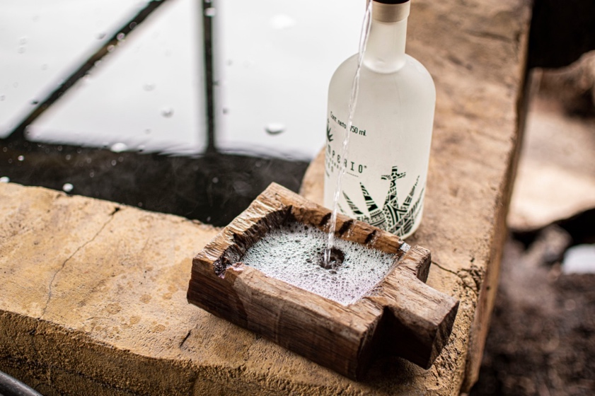 Product shot of Sacro Imperio being poured into rustic wooden basin